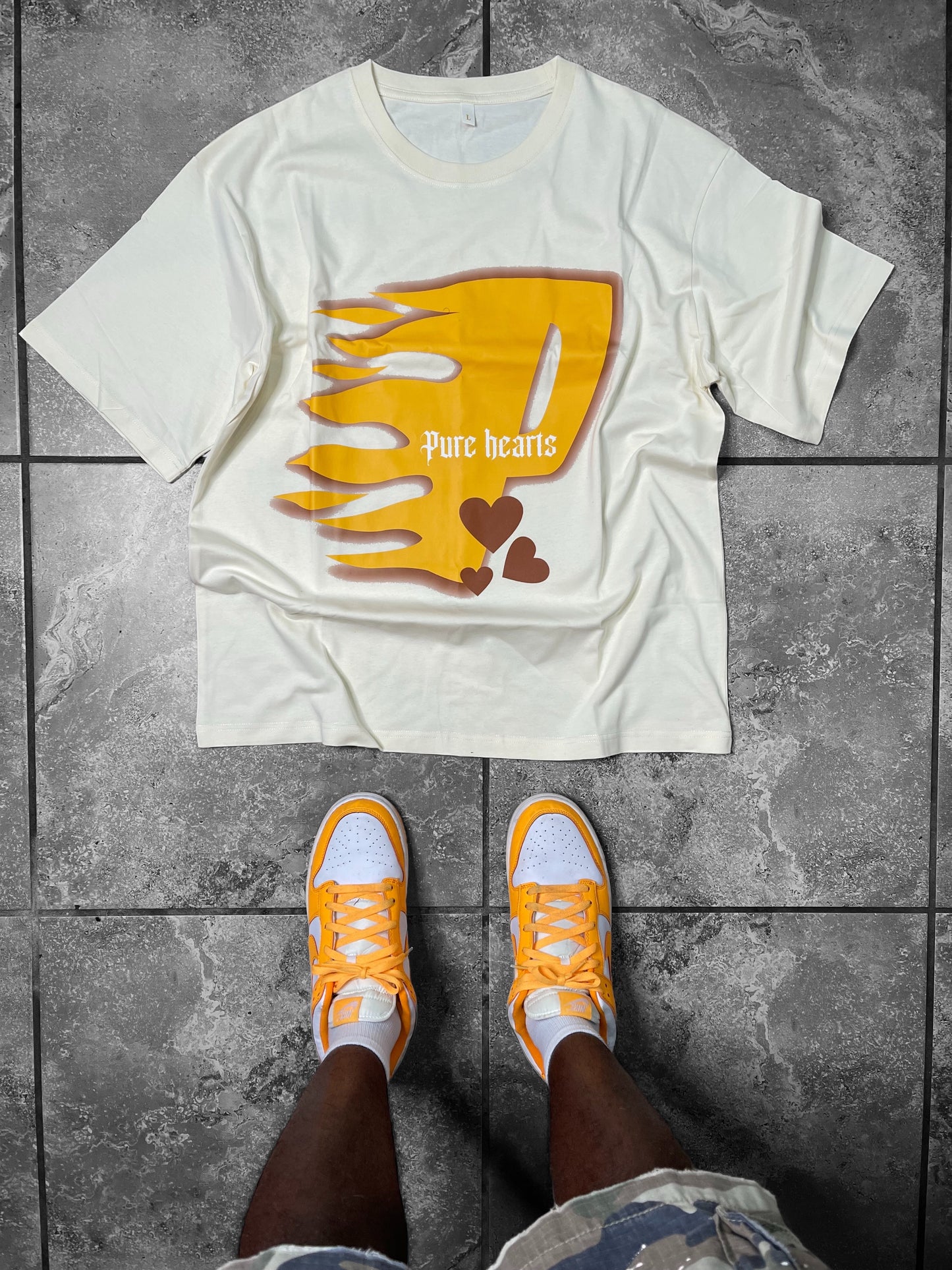 Vibrant design on front of a cream graphic tee, showcasing dynamic flames and bursts of color, a true expression of creativity placed on a dark floor to make the shirt stand out.